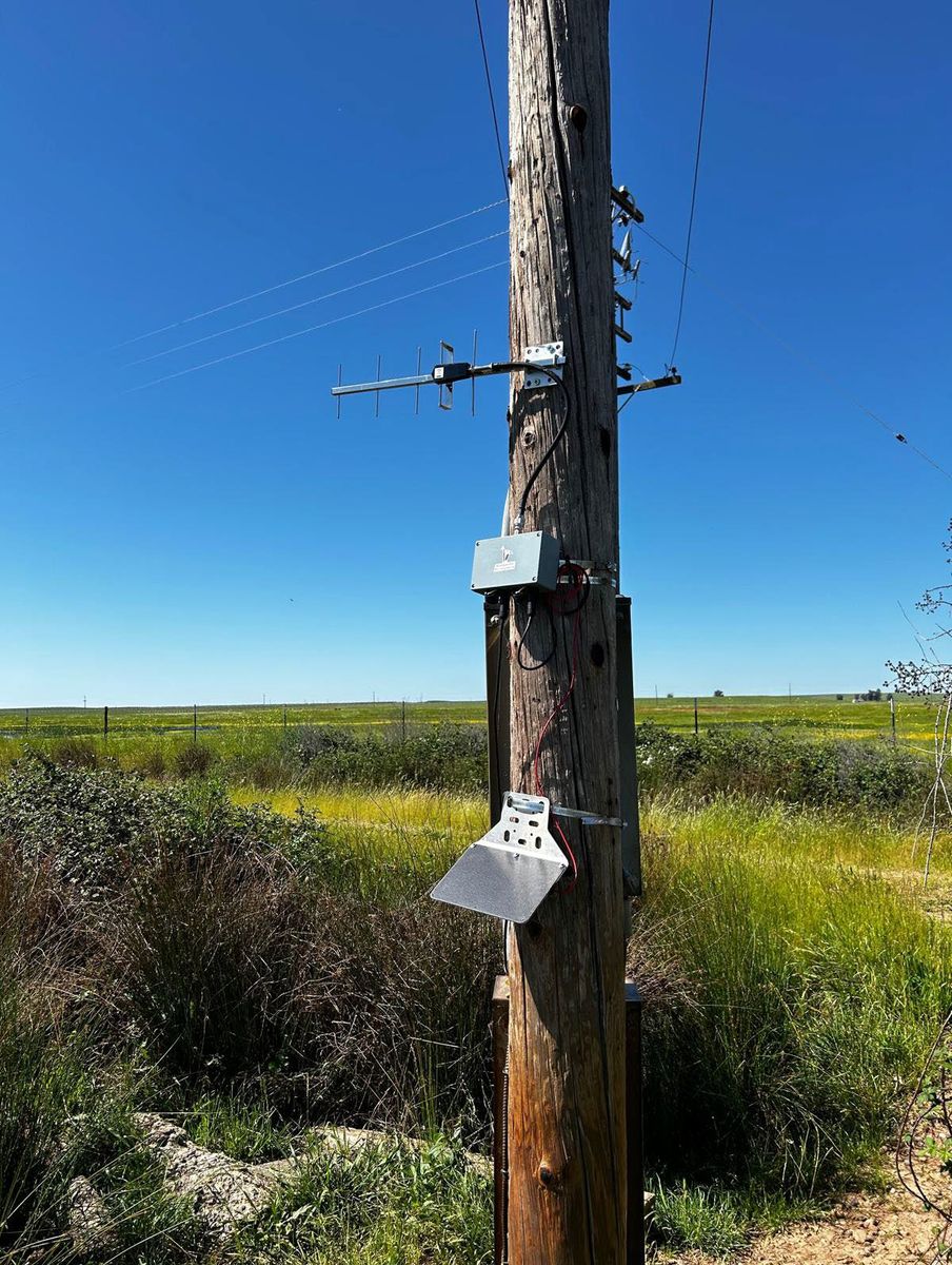 Telemetry unit mounted on a wooden utility pole beside a field